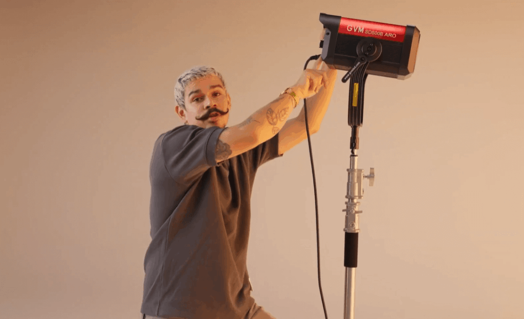 LED vs. Tungsten vs. HMI: Choosing the Right Film Light for Your Project 7 A gaffer adjusting a GVM panel film light on a C-stand, creating a warm glow.