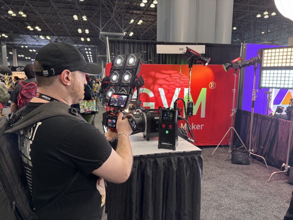 Beyond the Booth: GVM Unveils the Future of Lighting at BILD Expo 2025 3 A professional photographer uses a DSLR camera to capture a high-quality image of the new GVM Reign R1200B professional film light on display at the BILD Expo 2025.