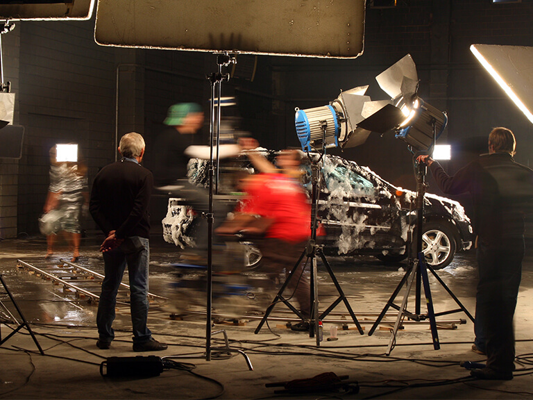 A bustling video shoot, vividly lit by professional continuous lights, demonstrating their crucial role in high-quality film and video production.
