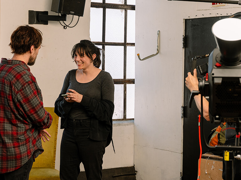 Filmmakers discussing a scene on set, with cinematic lighting equipment and softboxes in the background, setting the visual atmosphere for film production.