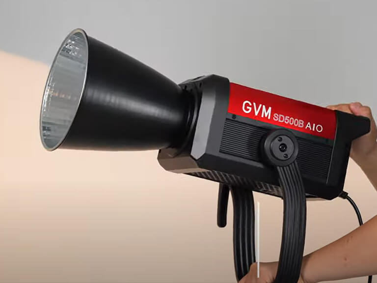 Mastering Lighting for Video Production at Movie Studio 7 Hands adjusting a GVM BD500B A10 LED light with a reflector dish, illustrating a portable solution for lighting for video production.