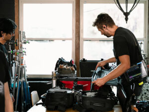 Professional videographer setting up GVM Z100B 100W portable LED light for on-location video shoot.