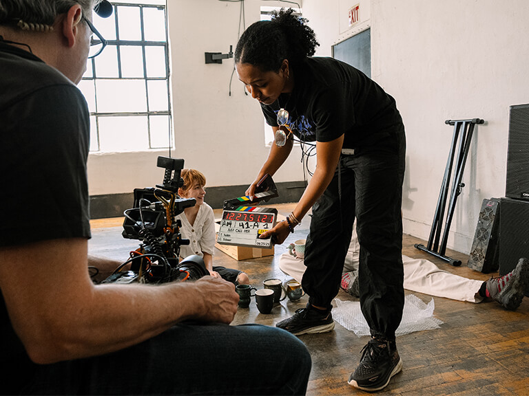 A film production crew meticulously setting up filming light and camera equipment on set, embodying the practical application of cinematic lighting techniques and equipment selection for professional video production.