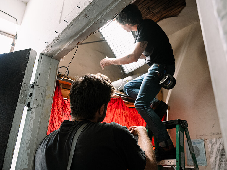 Mastering Lighting for Video Production at Movie Studio 5 Film crew members adjusting a large softbox light, demonstrating hands-on work in professional lighting for video production.