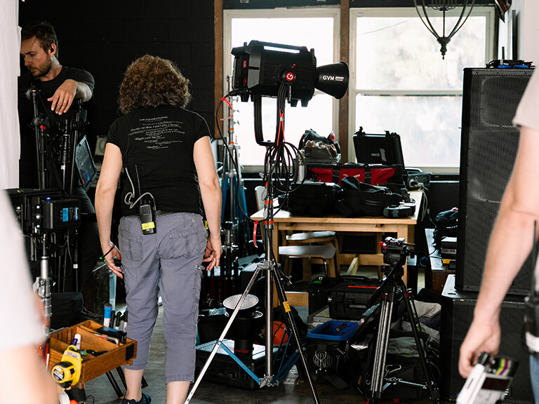 Mastering Your Light: A Deep Dive into Video Lighting Parameters 2 Film crew engaged in video production, with a professional adjusting a large video lighting fixture and another operating the camera, illustrating on-set lighting setup.