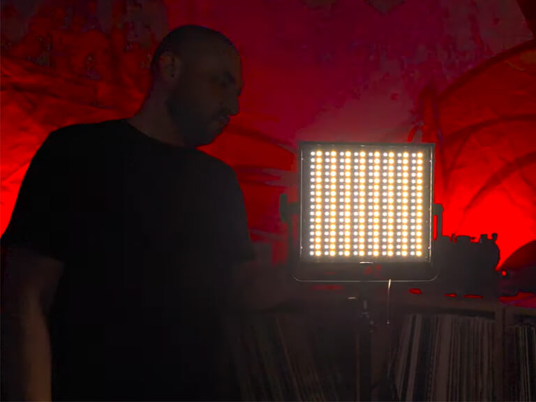 Podcast Background Lighting Ideas: Add Ambiance & Depth to Your Studio 6 A person silhouetted against a dramatic red-lit background, created by an LED panel light, demonstrating the use of color to set a mood in a podcast video.