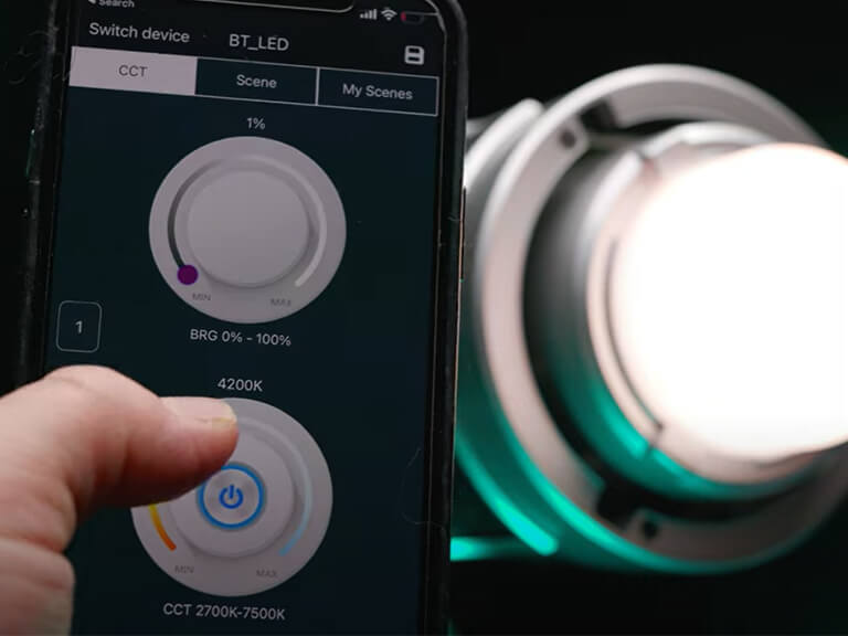 Podcast Background Lighting Ideas: Add Ambiance & Depth to Your Studio 7 A hand adjusting a light's physical control knob while a mobile app for smart lighting control is visible, illustrating versatile adjustment options for podcast studio lights.