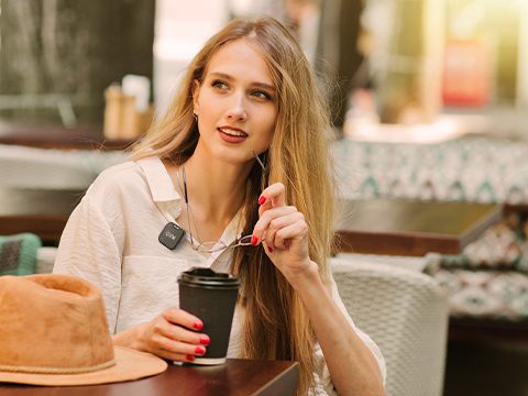 Beauty content creator recording a studio video wearing a compact GVM wireless lavalier microphone clipped to her sweater.