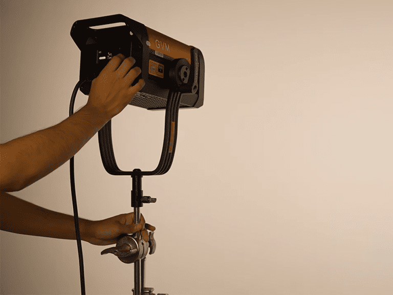 Adjusting the position of a GVM LED video light on a stand to optimize product photography lighting for camera settings.