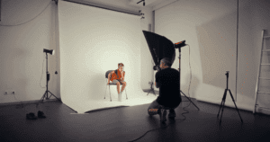 Indoor photography settings in a studio environment featuring a white backdrop, softbox light, and tripod for professional portraiture.